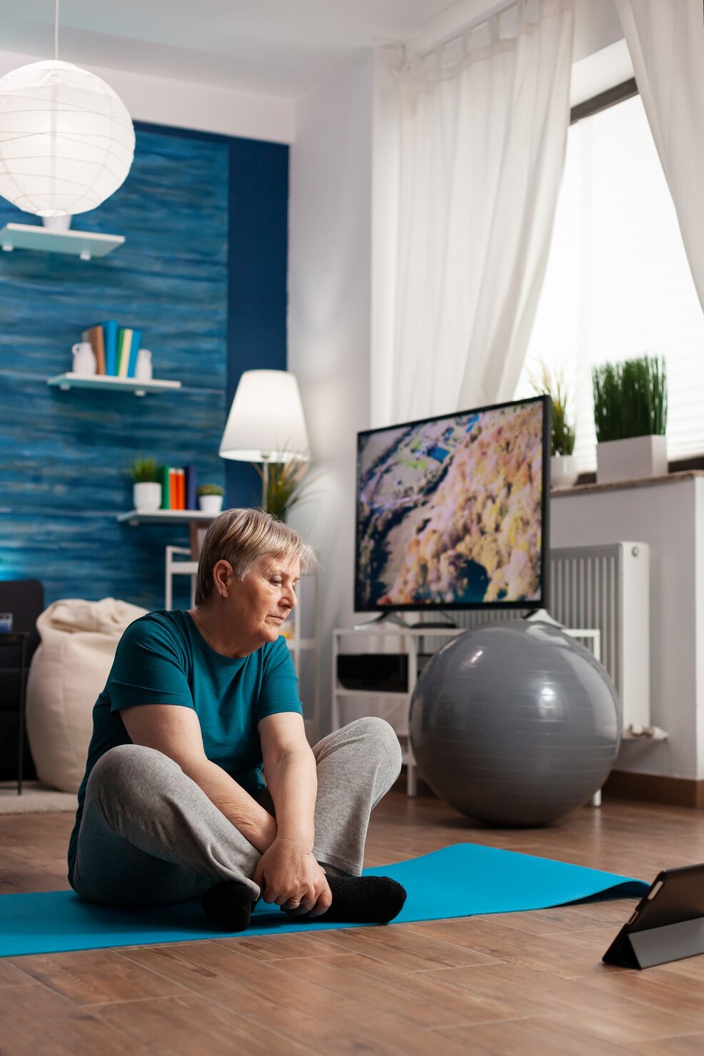 retired-senior-woman-sportswear-sitting-yoga-mat-watching-fitness-lesson-laptop_482257-8153